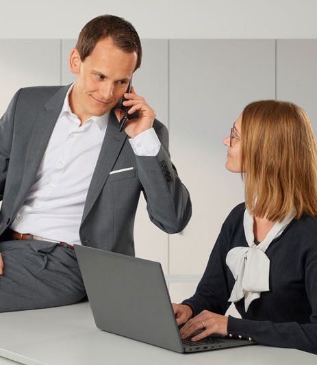 Herr Hölldobler telefoniert. Frau Hölldobler sitzend vorm Laptop. Gespräch zwischen Herr und Frau Hölldobler