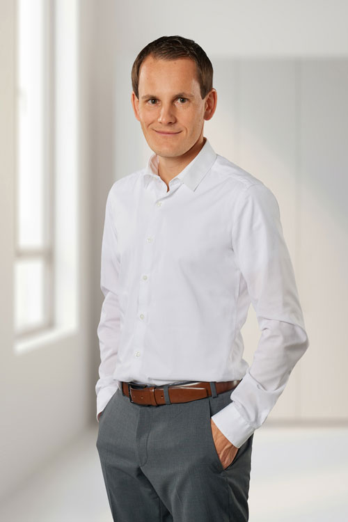 Herr Hölldobler im Business-Outfit stehend mit Händen in den Seitentaschen